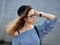 Young beautiful student girl in blue blouse and trendy glasses having fun posing on a river pier in city park