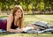 Young beautiful student girl on campus park grass with books studying happy preparing exam in education concept