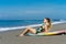 young beautiful surfer lying on surfboard on beach