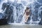 Young beautiful and sweet Asian woman in bikini getting body wet under stream of natural amazing waterfall sitting on rock feeling