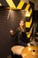 Young beautiful tattooed girl in a leather jacket plays drums in a recording Studio on the bright black and yellow band