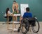 Young and beautiful teacher teaching cute down syndrome girl while disabled boy on wheelchair painting and drawing on paper in