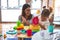 Young beautiful teacher and toddler playing with plastic food and cuttlery toys at kindergarten