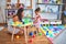 Young beautiful teacher and toddler playing with plastic food and cuttlery toys at kindergarten