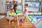 Young beautiful teacher and toddler playing with plastic food and cuttlery toys at kindergarten