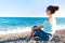 Young beautiful teenage girl sitting on Mediterranean Sea pebble