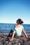 Young beautiful teenage girl sitting on Mediterranean Sea pebble beach