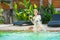 Young beautiful teenage girl sitting near exotic swimming pool with coconut and having fun in water