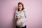 Young beautiful teenager girl pregnant expecting baby over isolated pink background disgusted expression, displeased and fearful