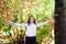 Young beautiful teenager girl tosses colorful autumn leaves in park