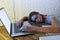 Young beautiful and tired student girl sleeping taking a nap lying on home laptop computer desk exhausted and wasted spending nigh