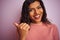 Young beautiful transsexual transgender woman standing over isolated pink background pointing and showing with thumb up to the