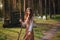 Young beautiful woma in medieval cowboy clothes, with a stick in hand. Barefoot on the ground. Against the background of the fores