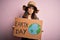 Young beautiful woman asking for planet conservation holding cardboard celebrating earth day with a confident expression on smart