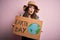 Young beautiful woman asking for planet conservation holding cardboard celebrating earth day scared in shock with a surprise face,