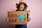 Young beautiful woman asking for planet conservation holding cardboard celebrating earth day screaming proud and celebrating