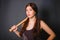 Young beautiful woman with a baseball bat in her hands. Fashionable studio photo on a gray background in the gangster style.