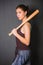 Young beautiful woman with a baseball bat in her hands. Fashionable studio photo on a gray background in the gangster style.