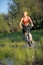 Young beautiful woman with bicycle going through water by the river