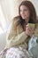 Young beautiful woman with blanket sitting by window