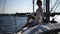 Young beautiful woman blonde in a bikinis and lace beach pareo sits on the deck of sailing yacht