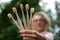 Young beautiful woman with blonde curly hair in pink hipster jacket and eyeglasses holding five bamboo toothbrushes in