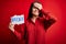 Young beautiful woman with blue eyes holding paper with brexit message over red background stressed with hand on head, shocked