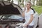 Young beautiful woman with a broken car on the road