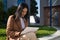 Young beautiful woman in brown coat sitting outside the office and working with her tablet. Business concept, telecommuting,