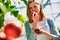 Young beautiful woman buyer smelling tomato in greenhouse