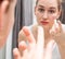 Young beautiful woman changing contact lenses in front of mirror