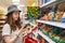 Young beautiful woman chooses products in the supermarket and checks the QR code on the label. The concept of modern technology