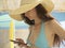 Young beautiful woman connecting with her phone at the beach