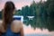 Young beautiful woman controls a white quadcopter by remote controller with a tablet. Focused on the drone, the pilot is out of