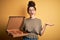 Young beautiful woman with curly hair and piercing holding delivery box with Italian pizza very happy and excited, winner
