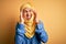 Young beautiful woman with curly hair wearing arab traditional hijab over yellow background with hand on headache because stress