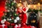 Young beautiful woman decorating Christmas tree with bauble - New Year tradition. Decorating Christmas tree at home