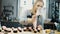 Young beautiful woman decorating the little cupcakes with cream from pastry bag. Blonde confectioner preparing an order.