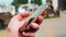 Young beautiful woman dial a text on the mobile phone in park. Close-Up Of a Woman Hand Dials SMS