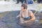 young beautiful woman dives into an ice hole on a winter day