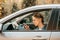 Young beautiful woman drives car, violates traffic rules, gets distracted, looks at screen of mobile phone, uses