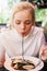 Young beautiful woman eating black pasta with seafood and cuttlefish ink in the outdoor restaurant. Funny and beautiful.