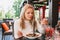 Young beautiful woman eating black pasta with seafood and cuttlefish ink in the outdoor restaurant. Funny and beautiful.