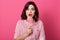 Young beautiful woman eating sweet candy isolated over pink isolated background, scared lady with surprise face, posing with fear