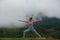 Young beautiful woman is engaged in hatha yoga in the morning misty mountains