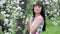 Young beautiful woman enjoying smell of blooming tree on a sunny day