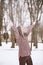 Young beautiful woman is enjoying the snow scattering it in the air, positive emotions, joy and happiness. Winter fun outdoors