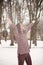 Young beautiful woman is enjoying the snow scattering it in the air, positive emotions, joy and happiness. Winter fun outdoors