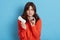 Young beautiful woman European young woman wearing orange sweater making choice between menstrual cup and hygiene pad, suffering