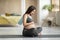 Young Beautiful Woman Expecting Baby Sitting On Yoga Mat And Embracing Belly